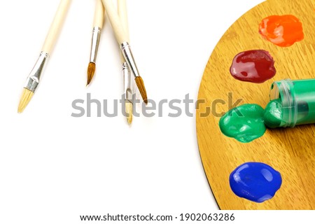 Artist brushes and palette with colored paints isolated on white background.
