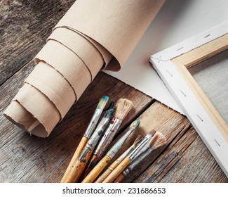 Artist canvas in roll, canvas stretcher and paintbrushes on old table - Powered by Shutterstock