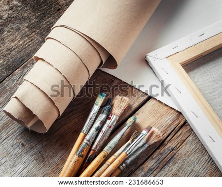 Artist canvas in roll, canvas stretcher and paintbrushes on old table