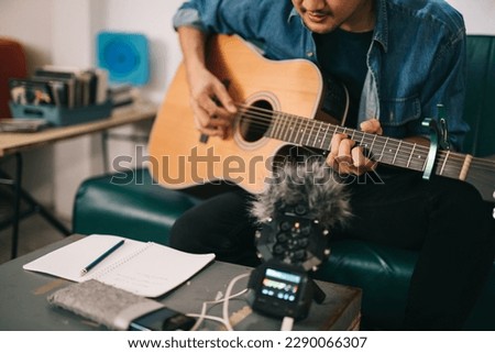 Artist composer in work process, A songwriter or composer, songwriter thinking and writing notes, lyrics in book. man playing live acoustic guitar.concept for musician creative. 