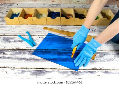 Artist cutting sheets of stained glass into small mosaic squares