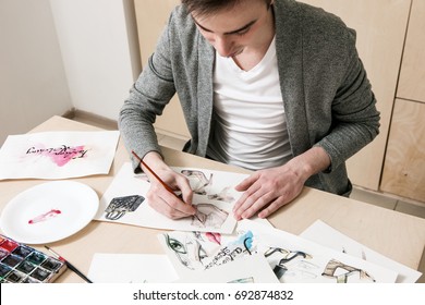 Artist doing design of fashion footwear model. Young man makes fashion sketch on his workplace with artistic tools around