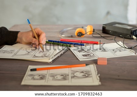 Artist drawing an anime comic book in a studio. Wooden desk, natural light. Creativity and inspiration concept.