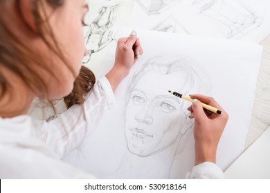 Artist drawing pencil portrait close-up. Woman painter creating picture of woman on big whatman. Art, talent, craft, hobby, occupation concept