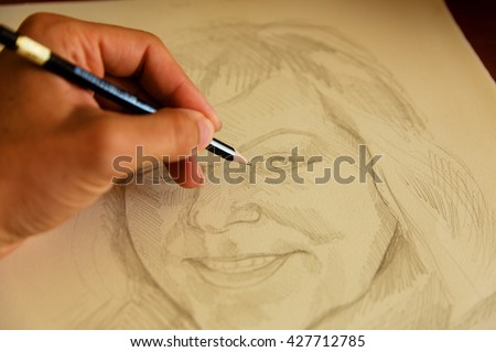 artist drawing woman portrait with a pencil.