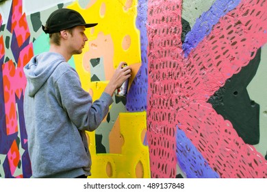 The Artist Draws Graffiti On A Fence.