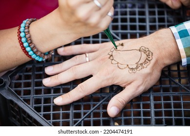 An Artist Draws A Henna Tattoo On A Man's Arm