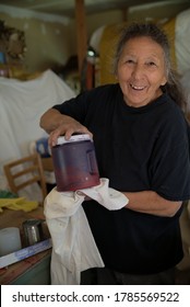 Artist holds a container of paint she has blended to use on her latest project.