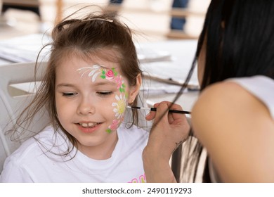 The artist makes a drawing on the girl's face with a face painting. High quality photo. High quality photo - Powered by Shutterstock