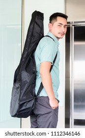 Artist Man Carrying A Guitar Case On The Shoulder In Room.