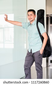 Artist Man Carrying A Guitar Case On The Shoulder In Room.