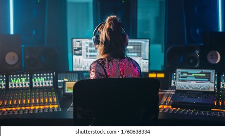 Artist, Musician, Audio Engineer, Producer In Music Record Studio, Uses Control Desk With Computer Screen Showing Software UI With Song Playing. Dances. Back View