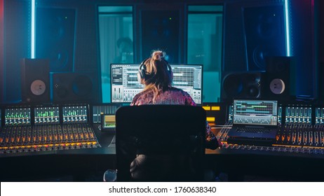 Artist, Musician, Audio Engineer, Producer In Music Record Studio, Uses Control Desk With Computer Screen Showing Software UI With Song Playing. Dances. Back View