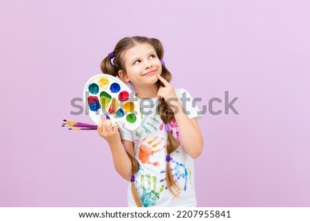 An artist on an isolated background, a little girl with paints in her hands, children's creativity.