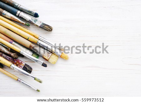 Artist paint brushes closeup on a white wooden background