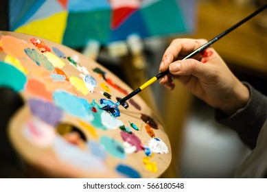 Artist Painting With Acrylic Colors And Mixing Tones On The Pallet. Blur Background Abstract Photo