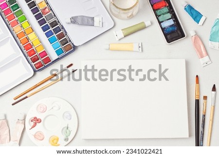 Artist painting color palettes, brushes and white canvas mockup. Craft hobby background. Recomforting, destressing hobby, art therapy