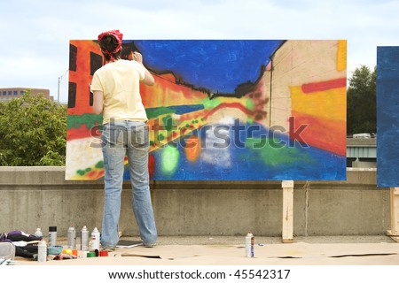 Artist painting on a wooden plywood canvas at an outdoor festival