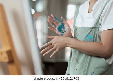 Artist with Paint-Splattered Hands in Apron Creating Art in Studio - Powered by Shutterstock