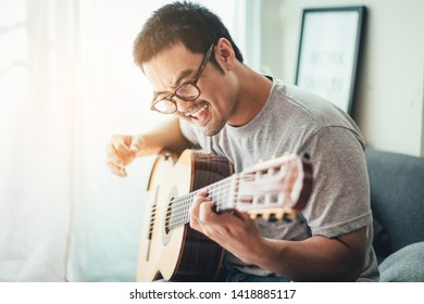 Artist Playing Acoustic Guitar,sing Folk Song.happy Man Sitting Enjoy On Sofa In Relax Time.concept For Art And Music Therapy For Relaxation And Healing For People