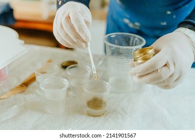 Artist prepairing ingredients for create clock in Resin art technique. Woman wearing rubber gloves mixing golden mica powdered pigment and medium. Selective focus. - Powered by Shutterstock