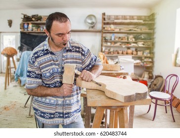 artist processing wood with a chisel in the studio