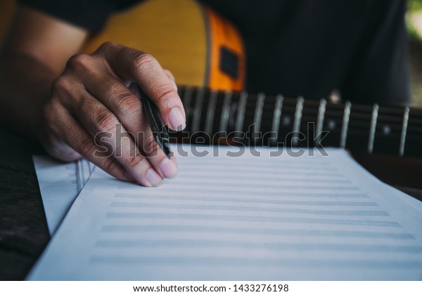 artist songwriter thinking writing\
notes,lyrics in book at studio.man playing live acoustic guitar\
relax chill.concept for musician creative.composer work\
process.people relaxing time with\
instrument.