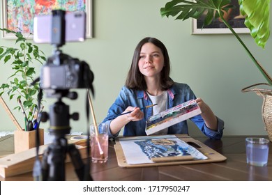 Artist, teenage girl, draws and records on video camera for his blog. Paints, drawings on a home table, camera on tripod, drawing telling girl blogger vloger. Technology, art, youth, education concept - Powered by Shutterstock