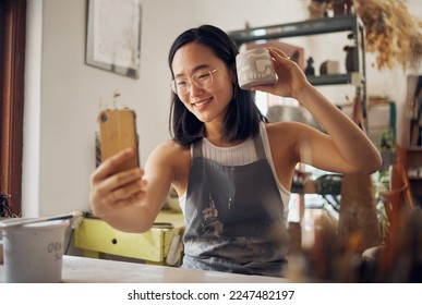 Artist woman, pottery and selfie with smile, design and product in studio to sell on internet, app or social media. Asian art girl, sculpture and smartphone with happiness, vision and artwork at desk - Powered by Shutterstock