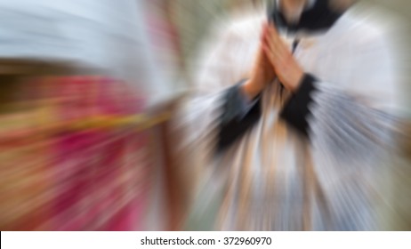 Artistic abstract radial blur edit of an altar boy or a mass server kneeling in surplice during the traditional tridentine latin catholic mass with his hands joined in prayer