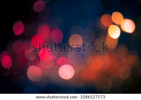 Artistic abstraction: mesmerizing display of circular illumination in rich tapestry of pigments, creating dreamlike atmosphere. Vivid palette showcases array of crimson, magenta, tangerine, and soft cerulean orbs with varying brightness and opacity, yielding visually intriguing layered effect. Blurred foreground combines warm tones including deep ruby and vibrant coral, seamlessly transitioning into cooler azure and navy in backgrounds. Luminous interplay suggests depth and dimension, inviting viewers to lose themselves in fluidity. Soft focus creates gentle quality, evoking sensations of warmth, celebration, and intimacy, ideal for festive or romantic ambiance. Composition emphasizes whimsy, suitable for creative projects including holiday marketing, party invitations, event promotions, or digital environments. Captivating imagery possesses emotive quality, leveraging exquisite coloration and intriguing bokeh effects to foster engagement and interpretation.