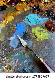 Artistic background. Oil paint palette knife spatula. Textured paint smudge stroke. Art color mixing with palette knife closeup. Paint stains. Multicolor tones, colours blend for artist painting.