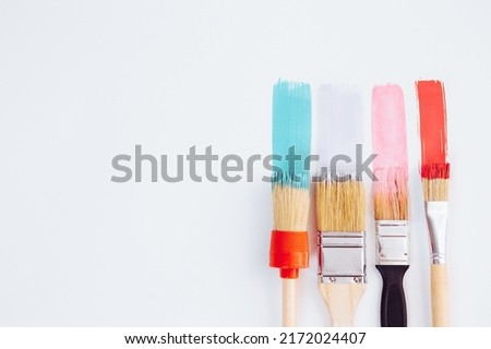 Artistic background. Paintbrushes are painting colorful brushstrokes on light background. Trendy pastel pink and mint colors of paint strokes. Mockup, art education, art class, wall painting