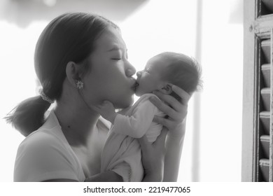 Artistic Black And White High Key Lifestyle Shot On Young And Happy Asian Chinese Woman Holding Adorable Newborn Baby Girl In Her Arms In Mother And Daughter Love Concept