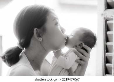 Artistic Black And White High Key Lifestyle Shot On Young And Happy Asian Chinese Woman Holding Adorable Newborn Baby Girl In Her Arms In Mother And Daughter Love Concept