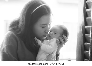 Artistic Black And White High Key Lifestyle Shot On Young And Happy Asian Chinese Woman Holding Adorable Newborn Baby Girl In Her Arms In Mother And Daughter Love Concept