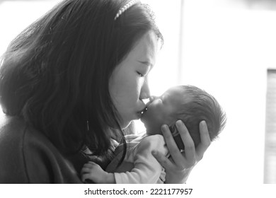 Artistic Black And White High Key Lifestyle Shot On Young And Happy Asian Chinese Woman Holding Adorable Newborn Baby Girl In Her Arms In Mother And Daughter Love Concept