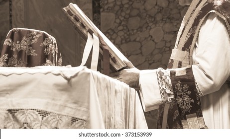 Artistic black and white/sepia vintage edit of a priest saying the extraordinary form, traditional latin tridentine rite Catholic mass