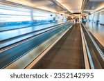 Artistic blur of airport from in focus moving walkway with blue and creamy yellow tones