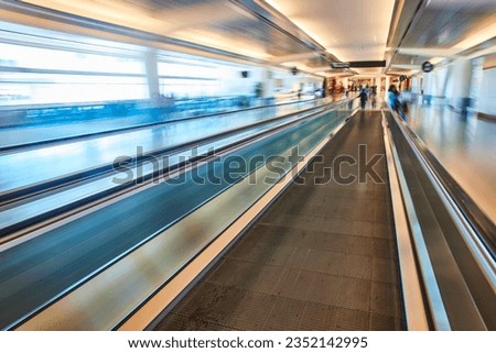 Artistic blur of airport from in focus moving walkway with blue and creamy yellow tones