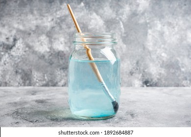 Artistic brushes in a jar with water on the gray rustic background. Artist tools. Selective focus. - Powered by Shutterstock
