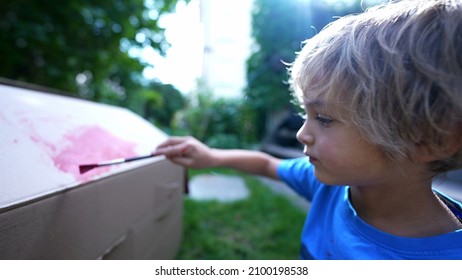 Artistic Child Painting Outside In Home Garden. Artistic Child Playing With Paint Outside In Garden Painting Cardboard Box