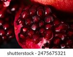 Artistic Close up Macro, Tropical open Pomegranate with seeds, also called Punica granatum. Photographed on a clean textured black background prepped ready to eat.