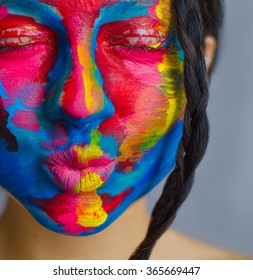 Artistic colorful portrait of a young beautiful model  with face covered with thick paint