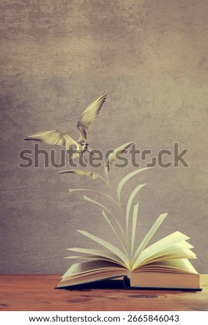 Artistic conversion of an open book on table with pages to become a flying bird in colour