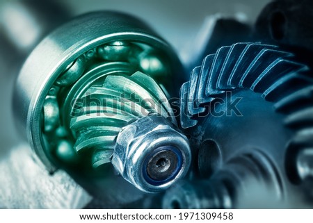 Artistic detail of steel gear wheels inside angle grinder machine in green blue shade. Mechanism of power tool engine with locking nut and ball bearing on cogwheel with pinion. Metallic cogged parts.