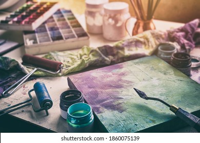 Artistic equipment - canvas and palette knife, paint brushes, multicolored paints in artist studio.