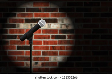 Artistic image of microphone against a rustic brick wall with spotlight effect and copy space.  Closeup with shallow dof.