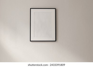 Artistic mockup template. Black vertical picture frames on beige wall background in sunlight. Poster display at home, minimal Scandinavian design, no people. Elegant apartment concept. Template