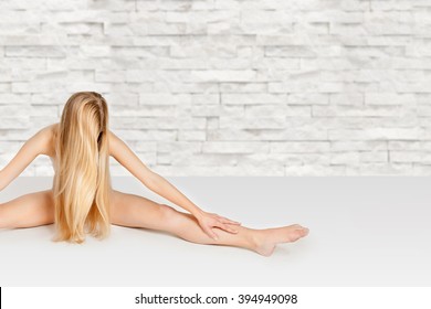 Artistic nude of beautiful flexible woman with very long blond hair, her private parts are not visible, photo with copy space on the right side of the image